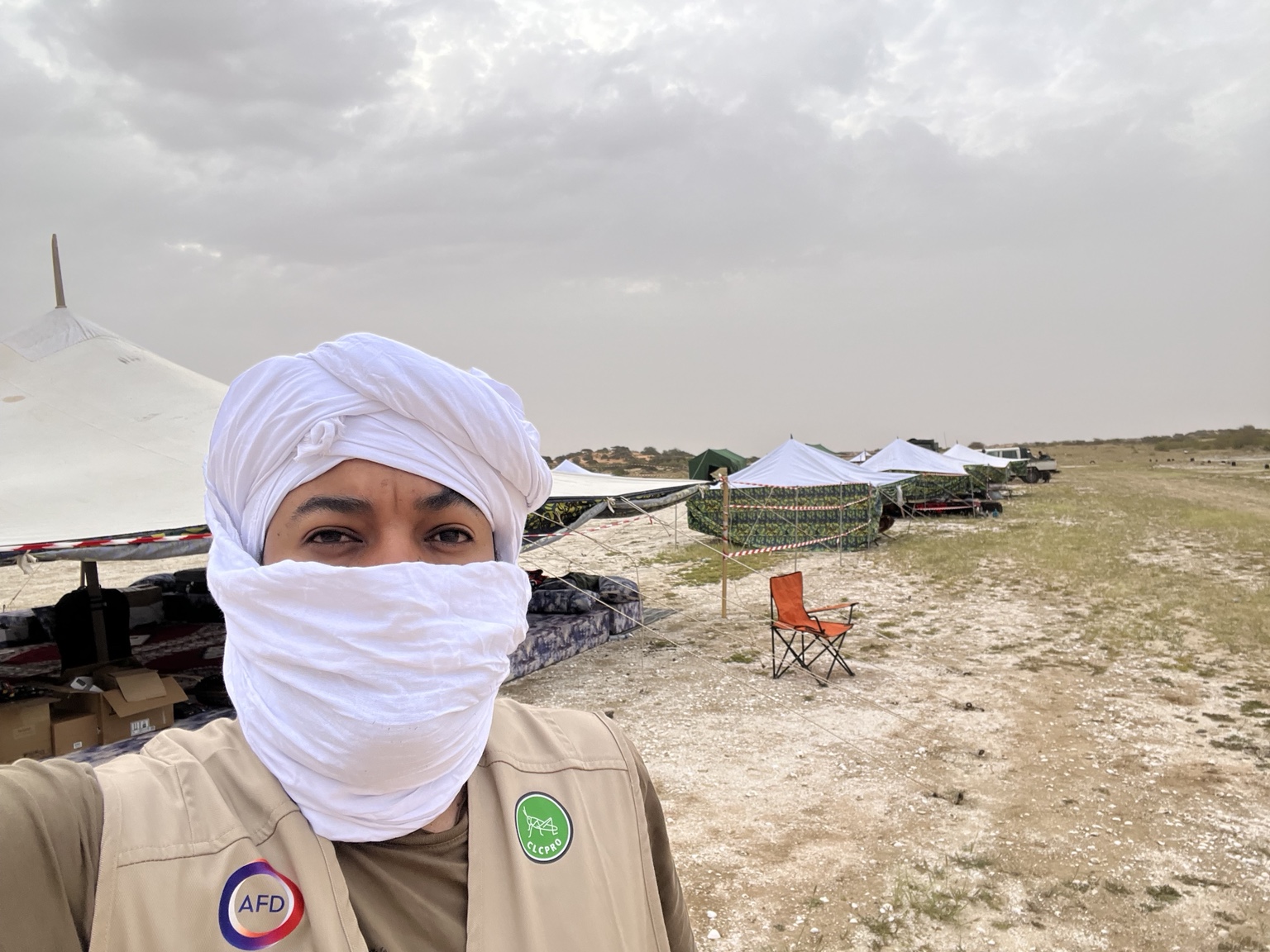 Dr. Daniel Gebregiorgis at an outdoor camp, wearing a white head wrap and field vest.